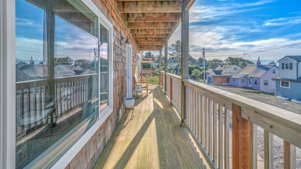 A wooden deck with a railing, large windows, and a view of neighboring houses. - Expansive Decks, Two Living Areas with Fireplaces! (Lincoln City)