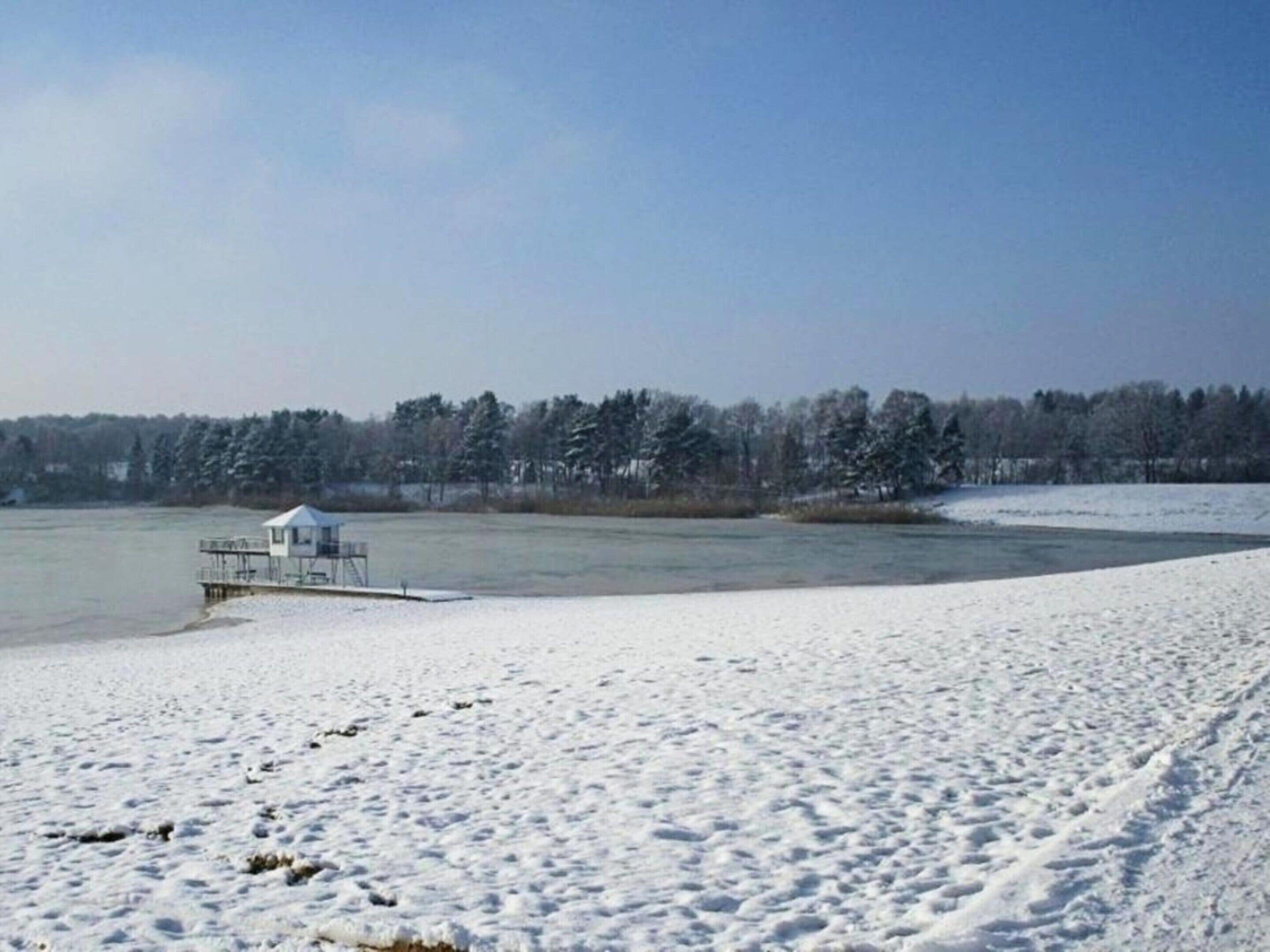 A snow-covered landscape with a small dock and a cabin.
