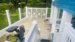 Une terrasse en bois avec une balustrade blanche, une petite table et une chaise.