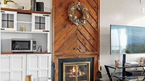 Ein Wohnzimmer mit Kamin, Holzregalen, einem Fernseher und einer Tierfigur.