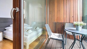 Una camera moderna con un letto, una porta in vetro, una zona salotto con tavolo e sedie e un muro in legno.
