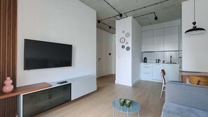 Un soggiorno moderno con una TV a schermo piatto, un tavolino consolle in legno e un divano grigio.