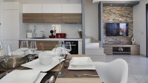 A modern kitchen with white cabinets, a stone backsplash, and a flat-screen TV mounted on the wall. - Lux Villas Afrodita Makarska (Makarska)