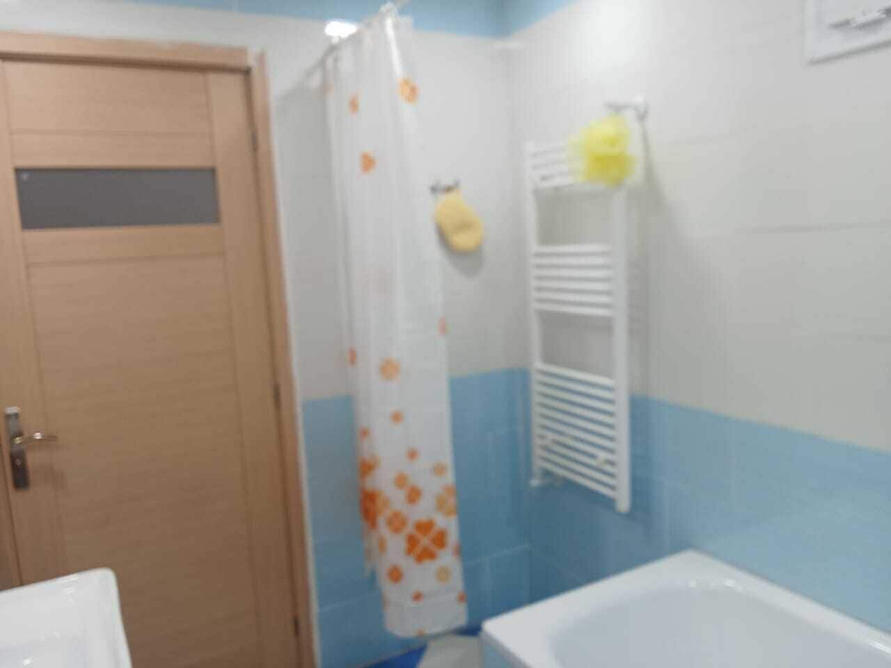 Un bany amb cortina de dutxa, paraigua per a tovalloles i banyera.