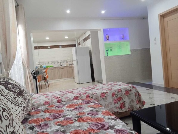 Ein Schlafzimmer mit Bett, Schreibtisch und Blick auf eine Küche und ein Wohnbereich.