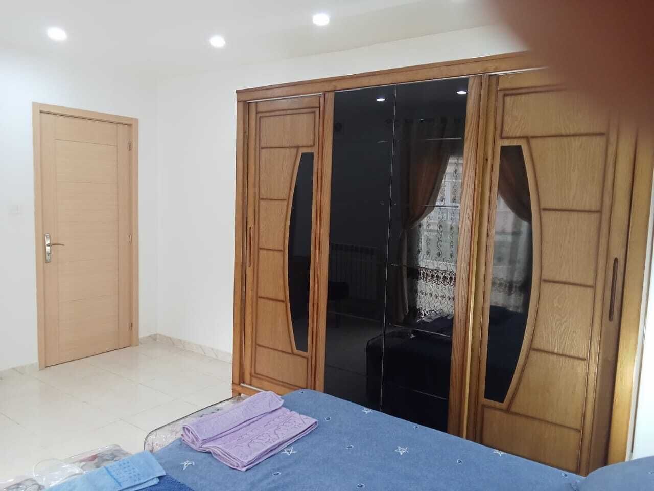 A room with a wardrobe, a door, and a table with items on it.
