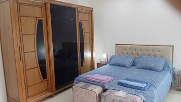 Un dormitorio con cama, armario y mesita de noche.