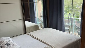 Ein Schlafzimmer mit Bett, Deckenventilator und Blick ins Freie.