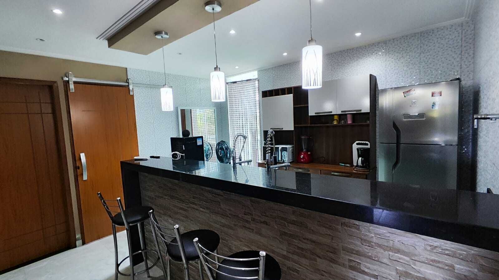 A modern kitchen with a black countertop, stainless steel appliances, and pendant lighting.
