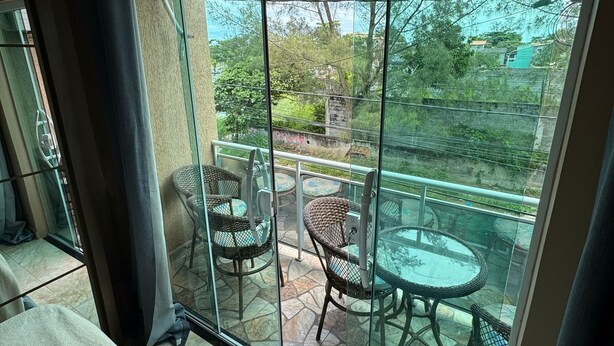 Ein Balkon mit Glastür, Korbstühlen und einem Glastisch.