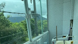 Ein Badezimmer mit großem Fenster, Waschbecken und Wäscheständer.