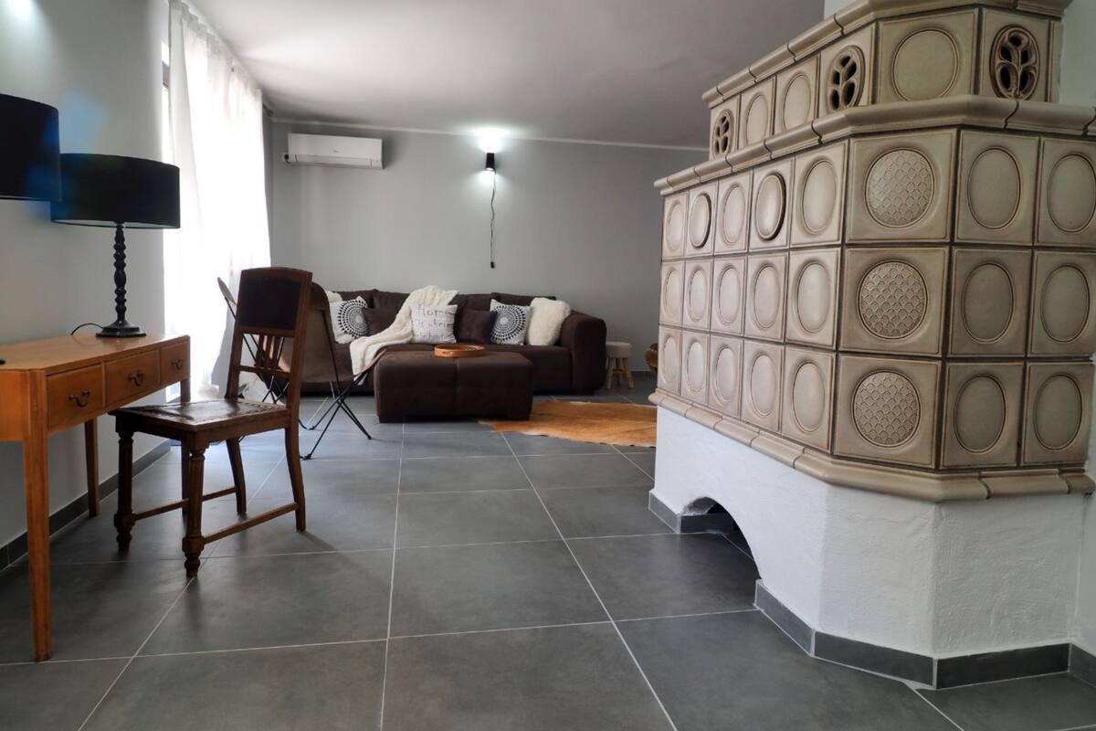 A living room with a sofa, a wooden chair, a desk with a lamp, and a decorative wall unit.