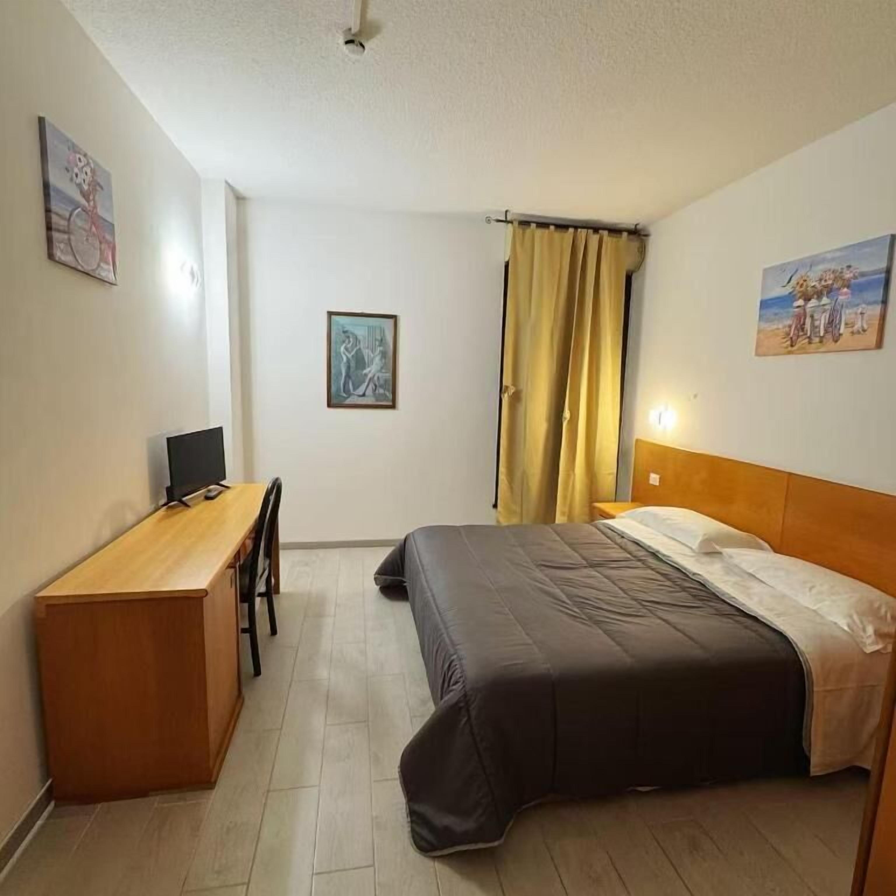 Una habitación con cama, escritorio y silla.