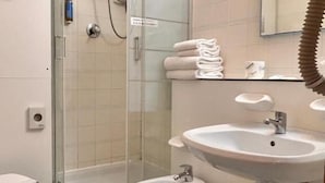 A bathroom with a glass-enclosed shower, a toilet, a bidet, and a sink.