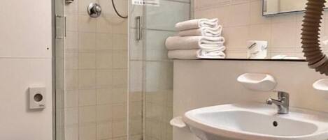 A bathroom with a glass-enclosed shower, a toilet, a bidet, and a sink.
