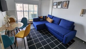 Uma sala de estar moderna com um sofá azul, uma mesa de jantar de vidro e um tapete xadrez preto e branco.