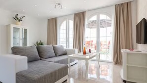 Ein modernes Wohnzimmer mit einer Couch, einem Couchtisch und einem Fernseher.