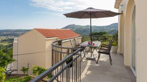 Ein Balkon mit Tisch und Stühlen, einem Sonnenschirm und einem herrlichen Bergblick.