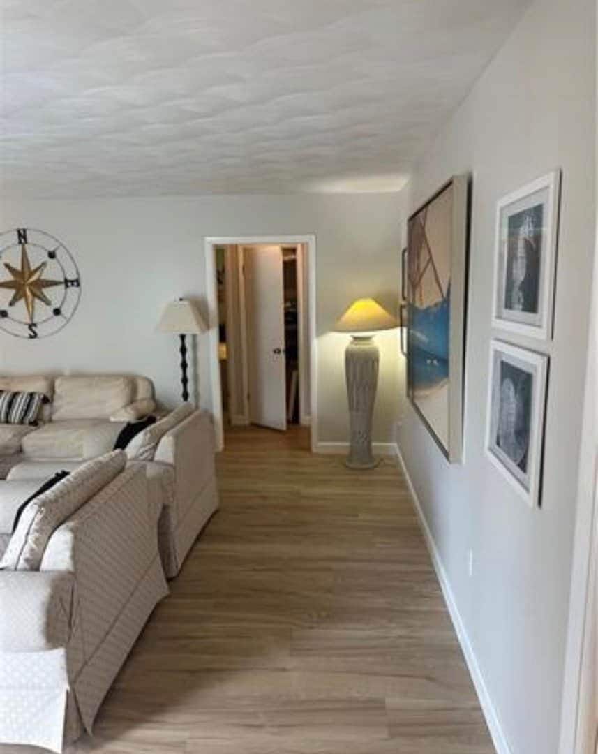 A hallway with a sofa, a lamp, and framed pictures on the wall.