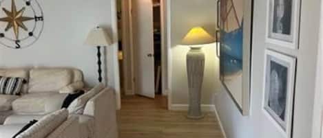 A hallway with a sofa, a lamp, and framed pictures on the wall.