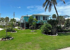 A two-story house with a well-maintained lawn and various tropical plants. - The Blue Retreat (Fort Myers Beach)