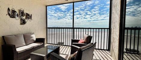 Een balkon met een bank, stoelen en een tafel.