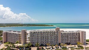 Een meerlaags hotel met uitzicht op het strand, een parkeerplaats en een heldere lucht.