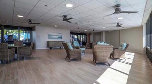 A spacious indoor area with wicker furniture, ceiling fans, and large windows allowing natural light. - Beach Watch (Bonita Springs)