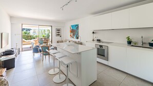A modern kitchen with a central island, bar stools, and a dining area with chairs. - Le Paradis avec deux terrasses équipées et piscine (Cannes)