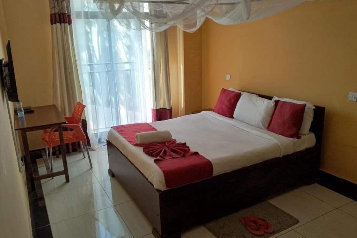 A hotel room with a bed, a desk, and a chair.