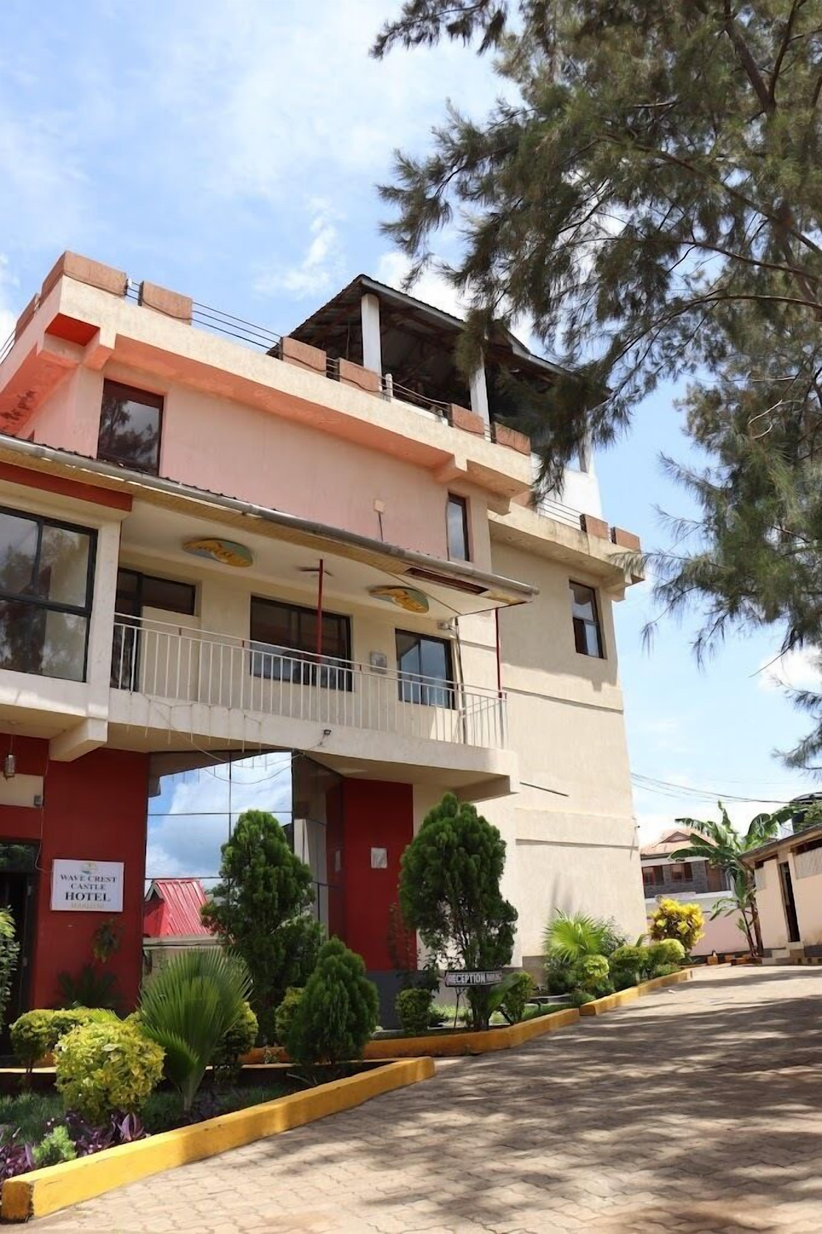 A hotel with a two-story structure, a balcony on the upper floor, and a landscaped garden area.