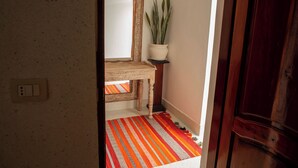 Un couloir avec un plancher en bois, un miroir, une plante en pot et une porte.