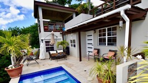 Una casa moderna con piscina, mobiliario de exterior y plantas en macetas.