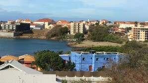 Un pueblo costero con edificios cerca de una masa de agua, incluyendo un edificio azul con una valla blanca en primer plano.