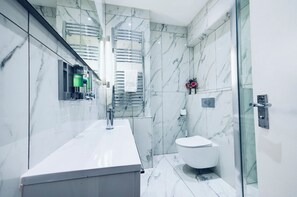 A modern bathroom with a marble backsplash, a glass shower enclosure, and a white toilet. - 5 minutes to Hyde Park! Family-sized condo. (London)