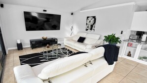 Ein modernes Wohnzimmer mit einem weißen Sofa, einem Glastisch und einem schwarz-weißen Teppich.