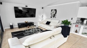 A modern living room with a white sofa, a glass coffee table, and a black and white rug. - Talita | Canal Home, Heated Pool & fanced Yard (Cape Coral)