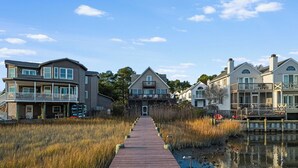 Une promenade en bois qui mène à une rangée de maisons situées au bord d’un plan d’eau.