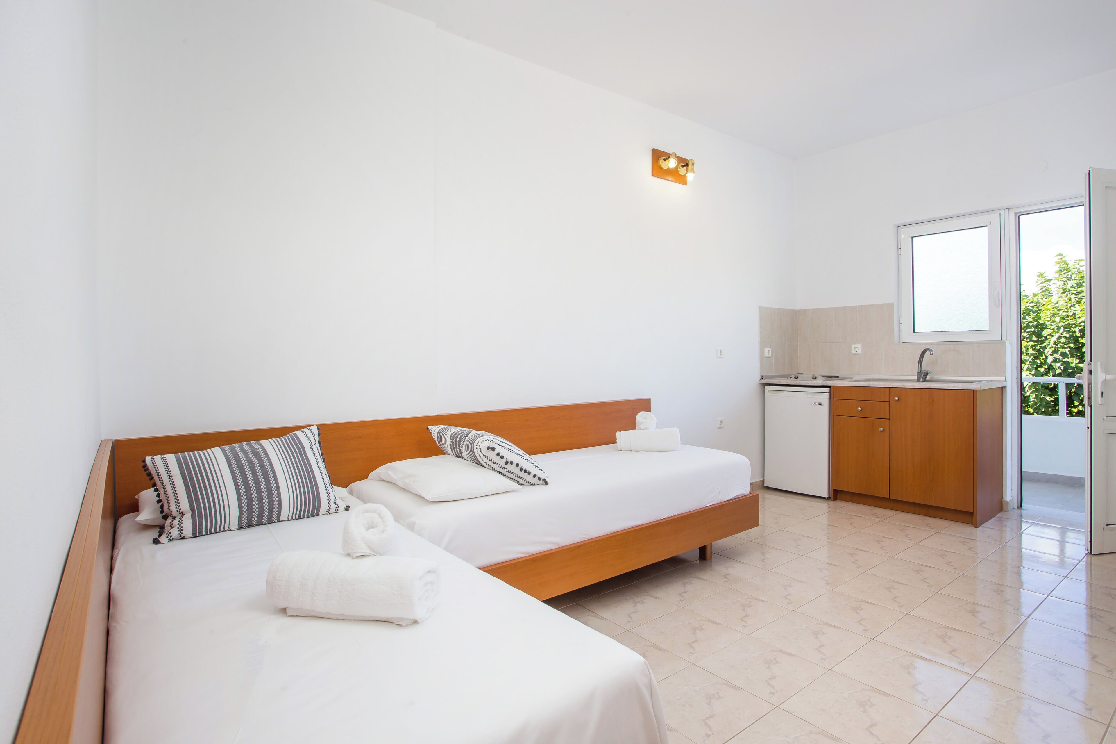 Una camera da letto con due letti, un angolo cottura e un bagno.