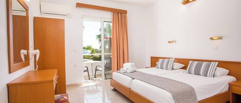 Una habitación de hotel con cama, escritorio, silla y puerta corrediza de vidrio a un balcón.