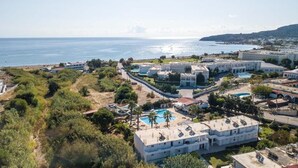 Vista aèria d'un hotel costaner amb diversos edificis, una piscina i vista al mar.
