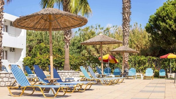 Zona de piscina amb gandules estampades i paraigües de palla.