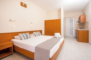 A hotel room with a wooden bed, a nightstand, a bathroom with a mirror and sink, and a wardrobe.