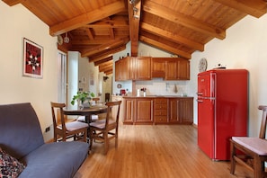 Una cucina con mobili in legno, un frigorifero rosso e un'area pranzo con divano e sedie.