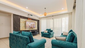 Ein modernes Wohnzimmer mit türkisfarbenen Sofas, einem großformatigen Kunstwerk mit Marmoroptik und einer Deckenleuchte.