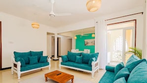 Ein Wohnzimmer mit zwei türkisfarbenen Sofas, einem Holztisch und einem weißen Deckenventilator.