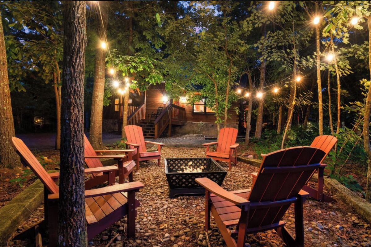 Gather around your private fire pit under twinkling string lights, where Adirondack chairs await cozy evenings beneath towering trees.