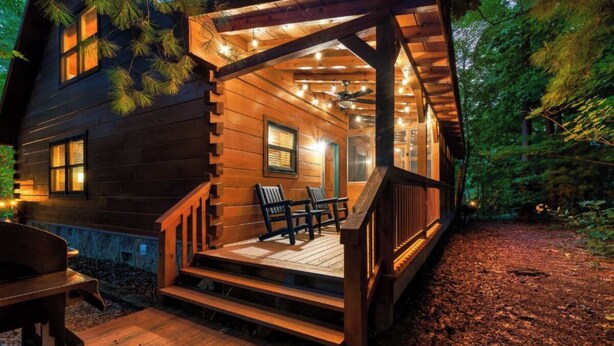 Eine Holzhütte mit Veranda, Sitzgelegenheiten im Freien und Lichterketten.