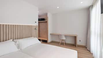 A modern hotel room with a bed, a desk, and a wardrobe.
