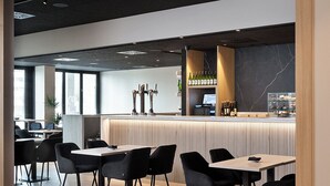 A modern restaurant with a bar area, wooden flooring, and black chairs. - Hotel Iriguibel Arrosadía (Pamplona)